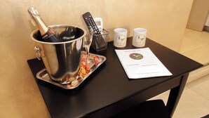 A table with a champagne bottle in a metal bucket, a remote control, two mugs, and a booklet. - Domus Gallo B&B (Rome)