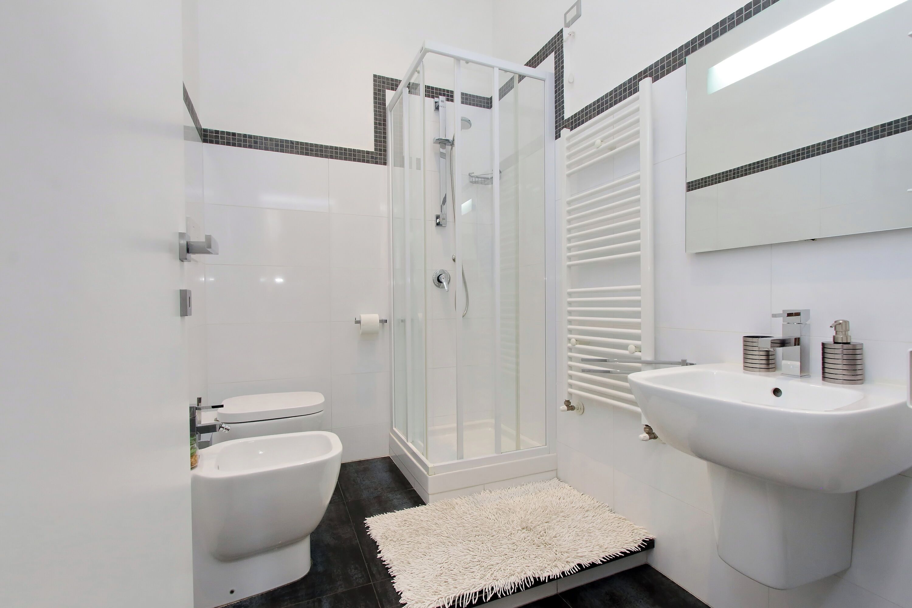 Een moderne badkamer met een douche met glazen wand, een witte wastafel en een toilet.
