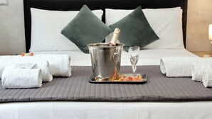 A bed with a metal bucket containing a bottle, a glass, and a tray with food items. There are two pillows and two rolled towels on the bed. - Domus Gallo B&B (Rome)