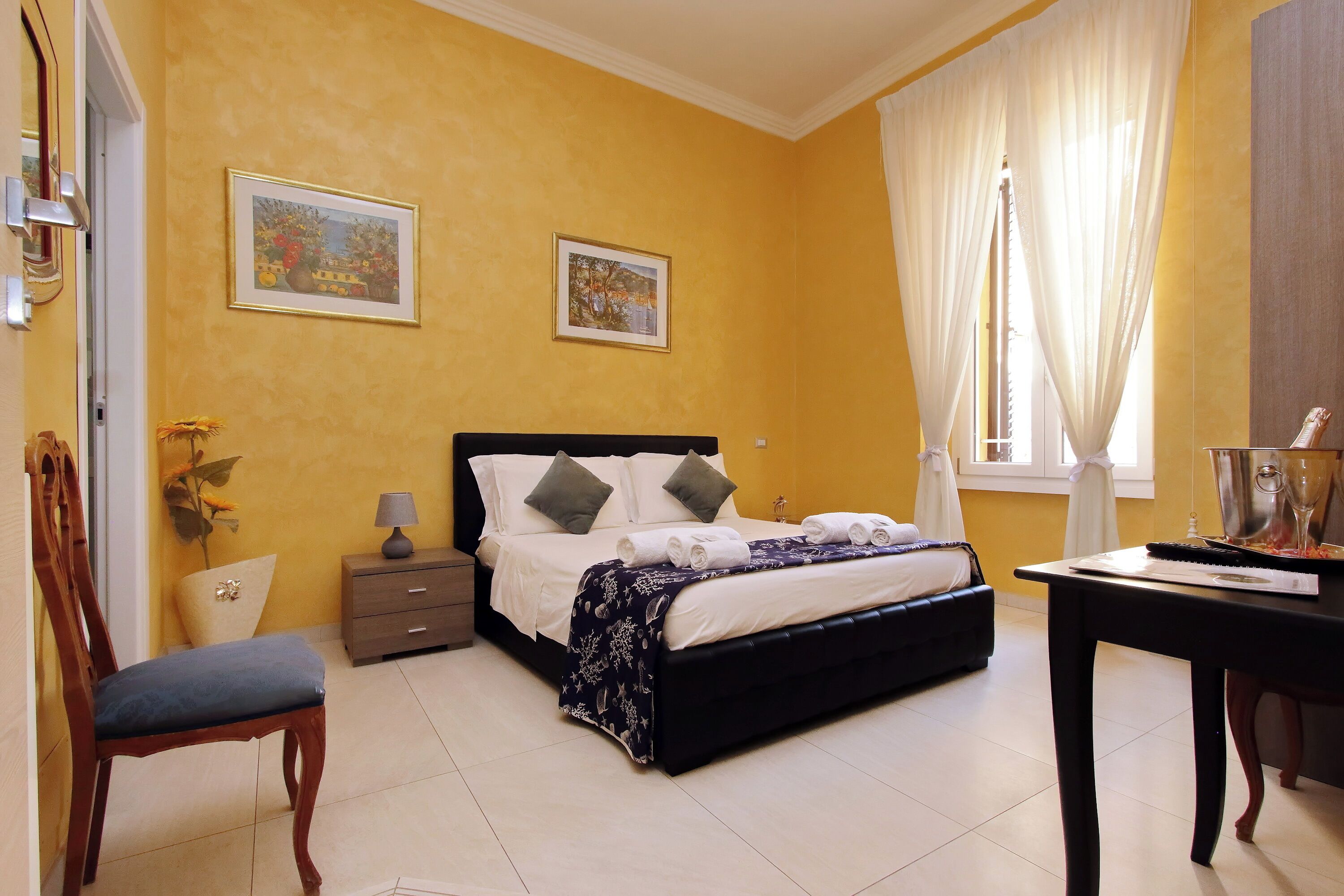 A bedroom with a bed, bedside table, chair, and a desk with a lamp.