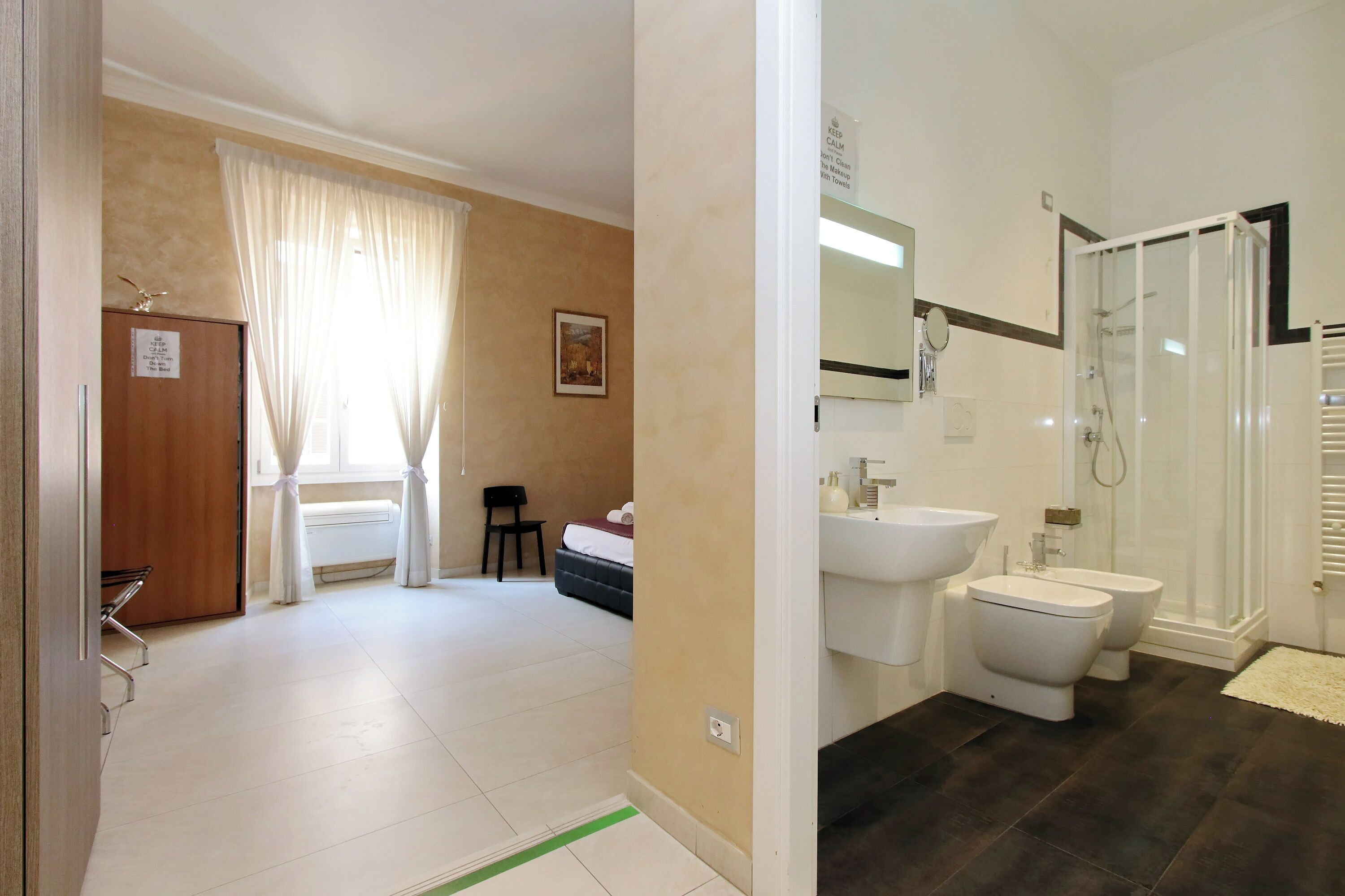A hotel bathroom with a shower, bidet, and sink.