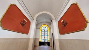 A hallway with a central arched doorway leading to a room with a stained glass window. - Domus Gallo B&B (Rome)
