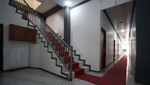 Un couloir avec un tapis rouge, un escalier doté de rampes en métal et un meuble en bois.