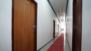 Un couloir avec des portes en bois, une moquette rouge et des murs blancs.