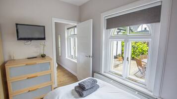 Een slaapkamer met een bed, een dressoir, een aan de muur bevestigde televisie en een raam met uitzicht.
