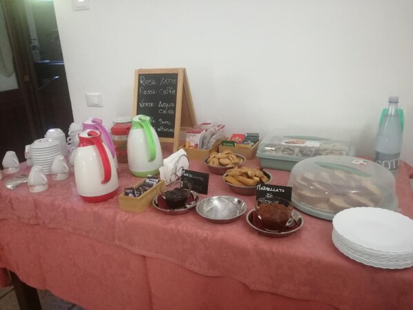 Una mesa de buffet con diferentes alimentos y bebidas, incluyendo un cartel que indica la disponibilidad de café y té.