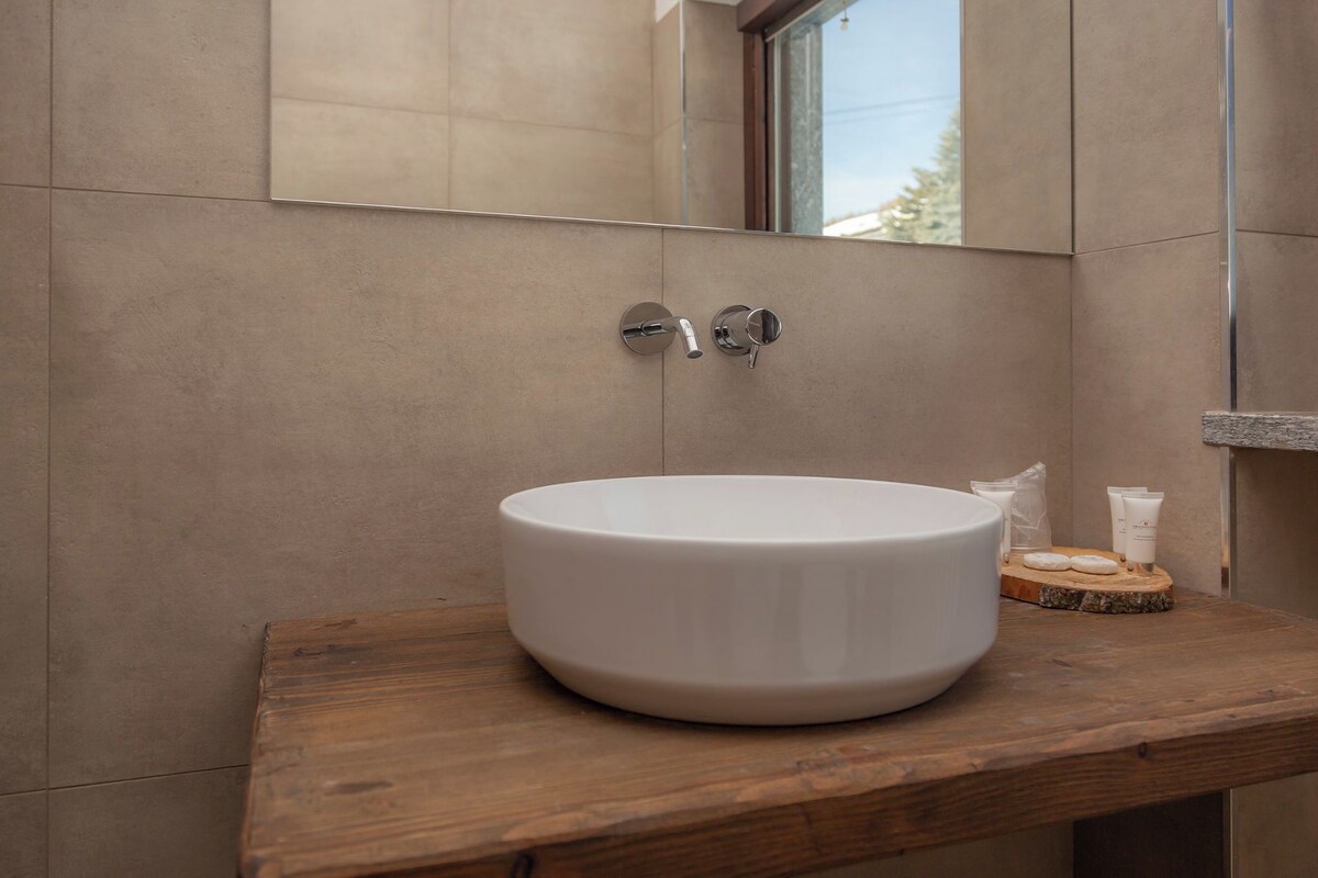 Un baño con un lavamanos redondo blanco, una encimera de madera y un espejo sobre el lavamanos.