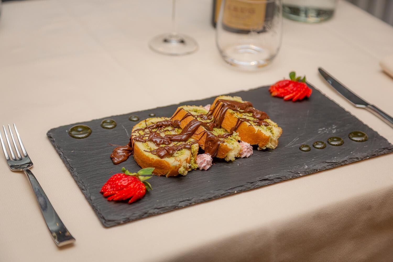 A dessert on a slate plate with a fork and knife on the table.