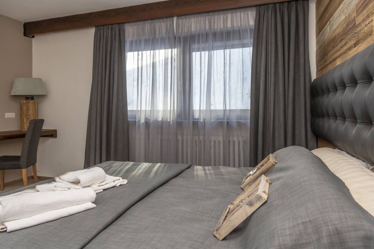 A hotel room with a bed, a desk, and a chair.