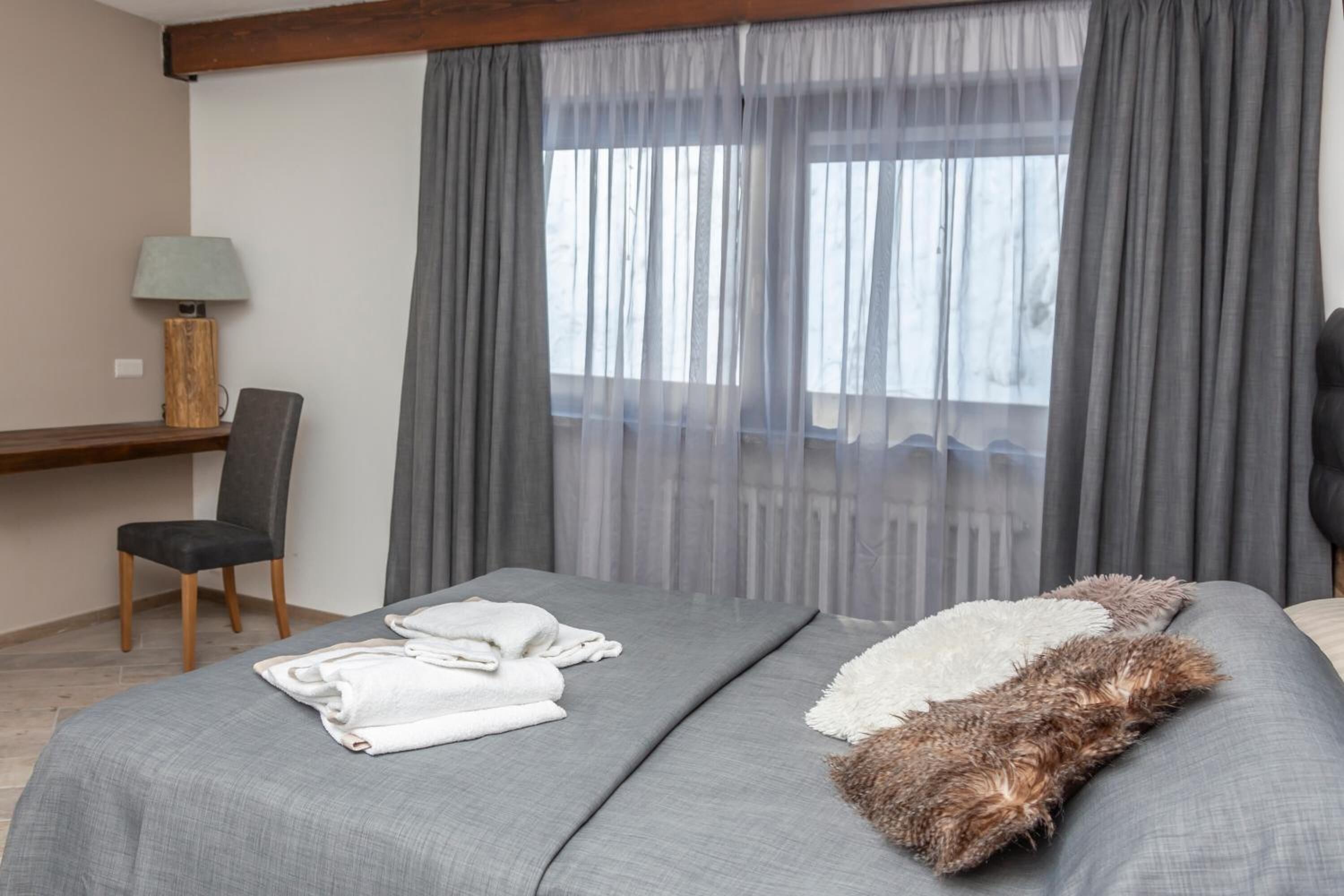 Una camera d'albergo con un letto, una sedia, una scrivania e una finestra con tende.