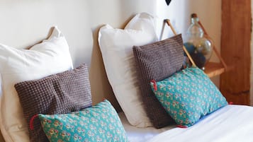 A bed with white bedding and two decorative pillows, one with a floral pattern and the other with a textured design.
