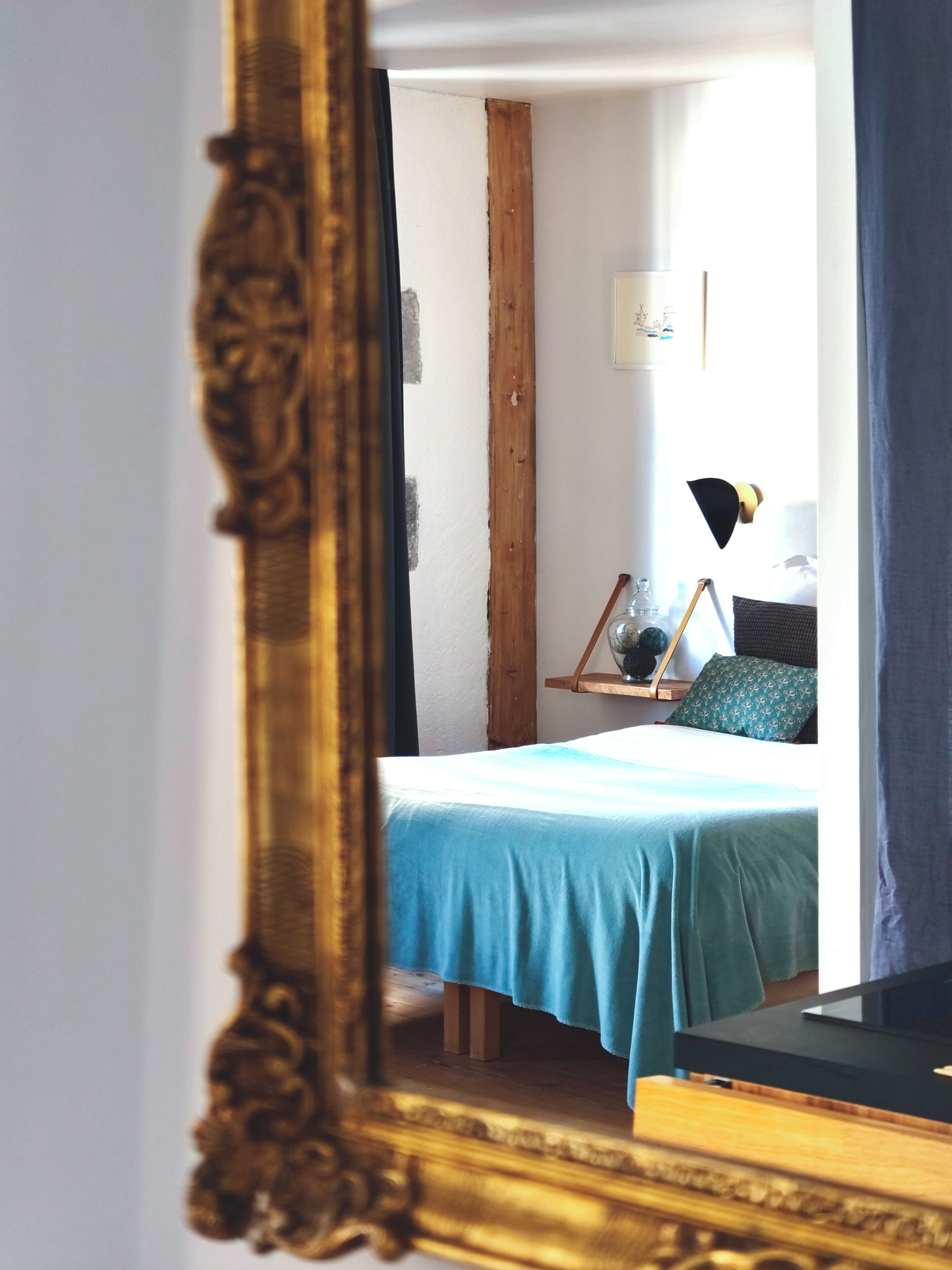 Ein Schlafzimmer mit einem Bett, einem Nachttisch, einer Lampe und einem Spiegel.