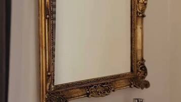 Une salle de bain avec un miroir encadré d’or, un lavabo blanc et des serviettes soigneusement pliées.