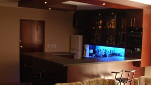 A kitchen with a bar area, wooden cabinets, and bar stools. - Shirleys Place (Cape Town)