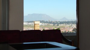 A room with a large window offering a view of a cityscape and mountains. - Shirleys Place (Cape Town)