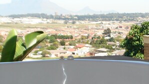 A hot tub with a view of a residential area and mountains in the background. - Shirleys Place (Cape Town)