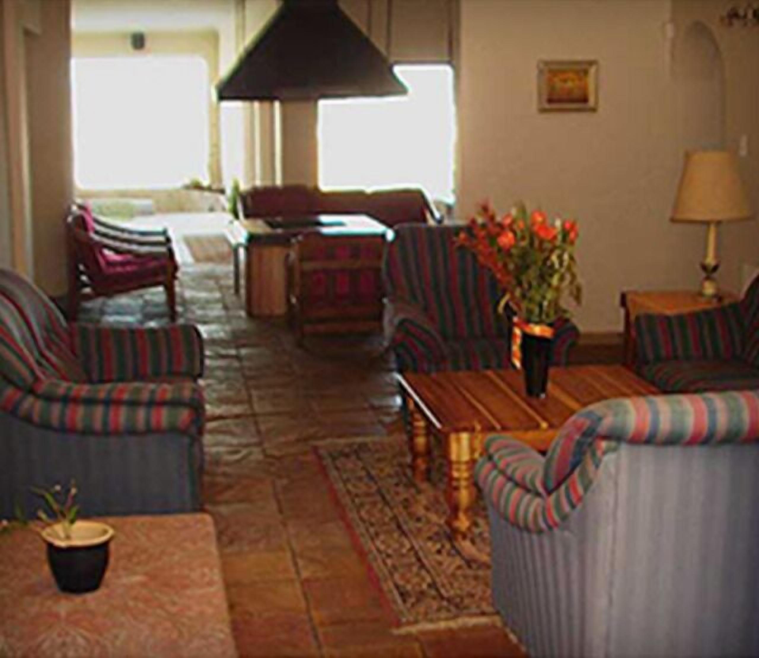 A living room with striped sofas, a wooden coffee table, and a vase with flowers.