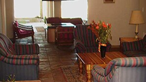 A living room with striped sofas, a wooden coffee table, and a vase with flowers. - Shirleys Place (Cape Town)