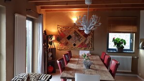 A dining area with a wooden table, red chairs, a chandelier, and a large decorative tapestry. - WOODEN HOUSE, chalet style (Lontzen)