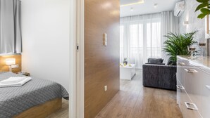 Ein modernes Hotelzimmer mit Bett, Nachttisch und kleinem Schreibtisch mit Lampe.