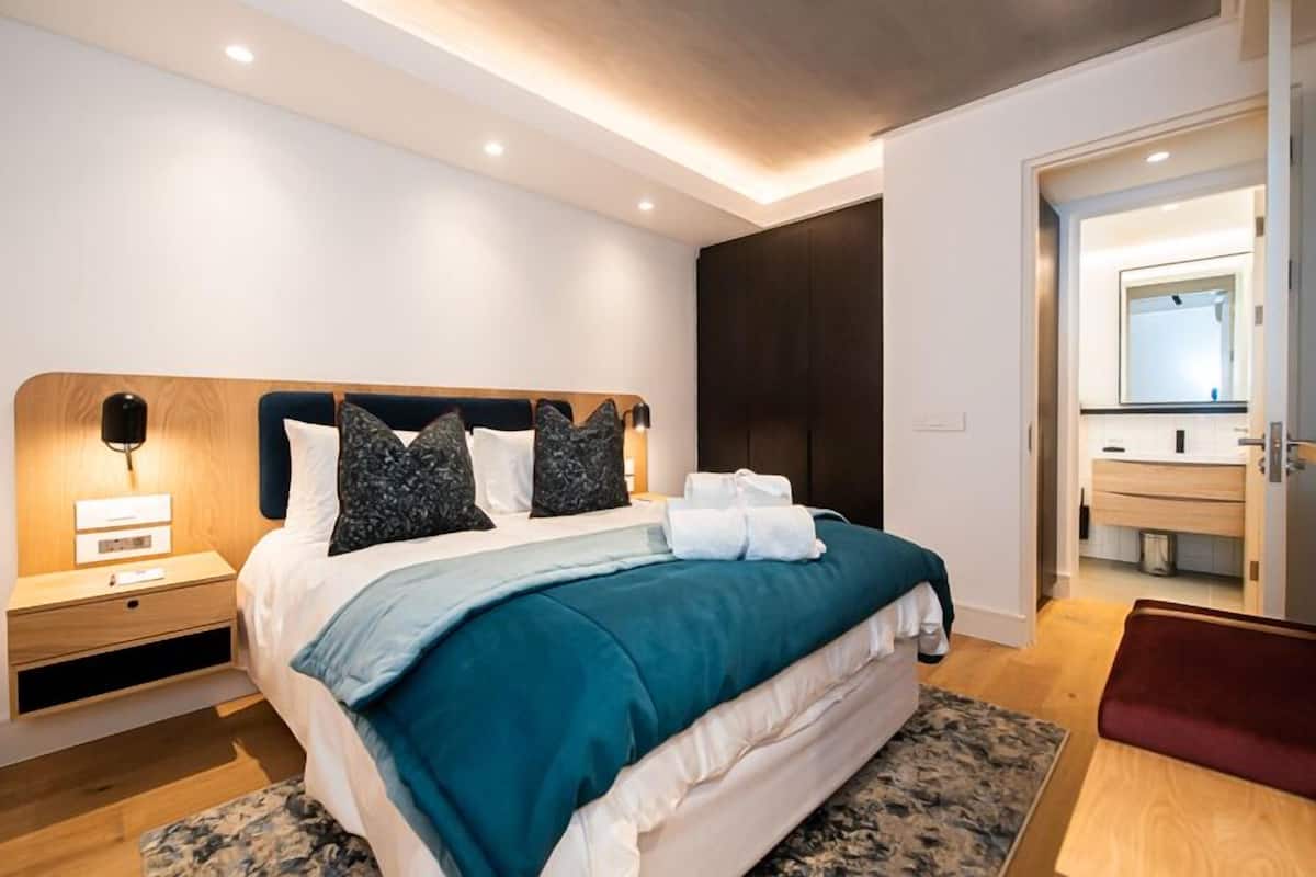 A modern bedroom with a large bed, a bedside table, a nightstand, and a built-in wardrobe.