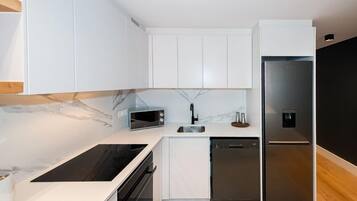 A modern kitchen with white cabinetry, a built-in microwave, a stainless steel refrigerator, and a dishwasher.