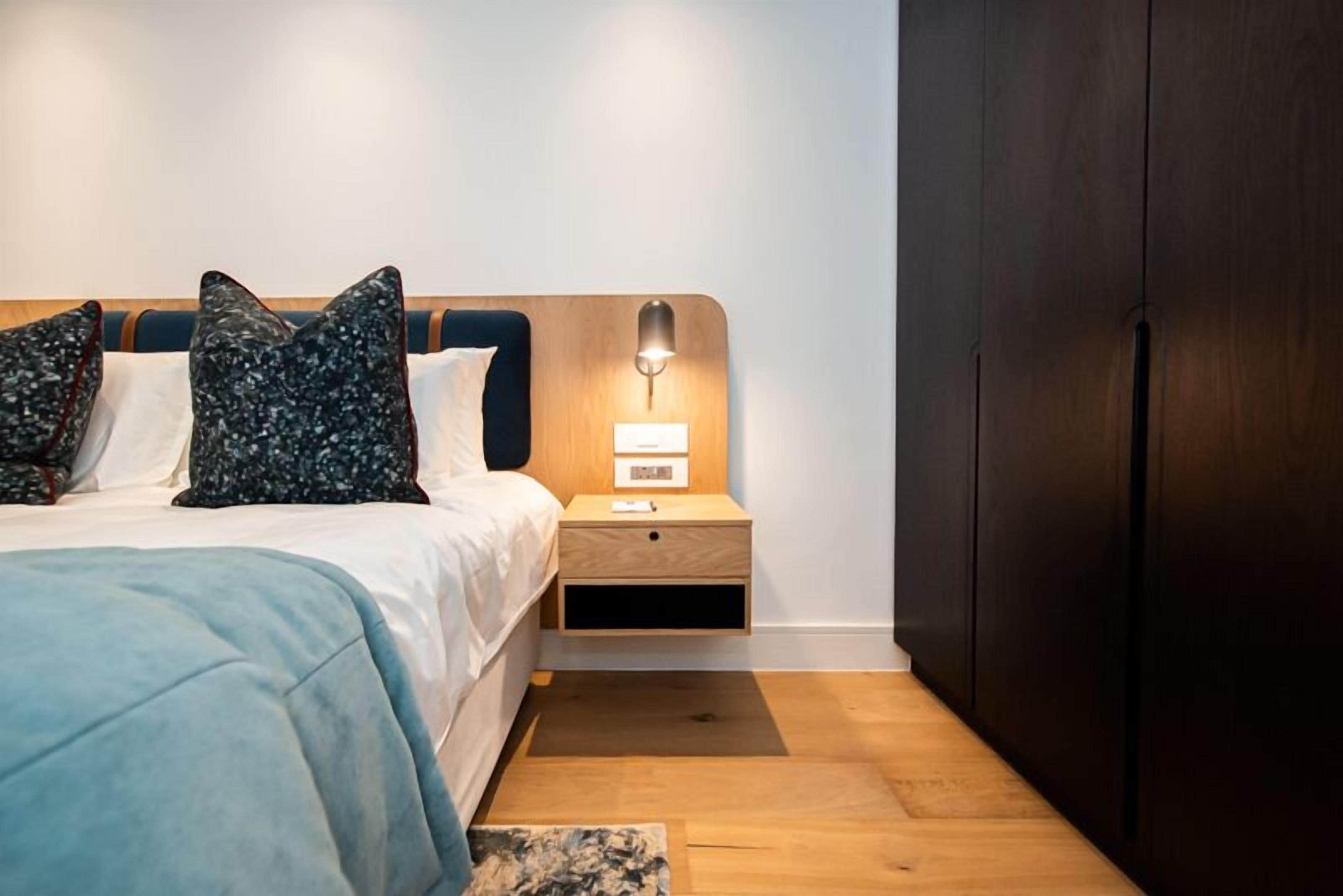 A bedroom with a bed, bedside tables, a nightstand, and a wardrobe.