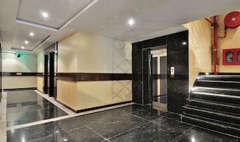 Una hall moderna con pavimento in marmo, una reception, un ascensore e una scala.