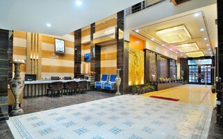 Una hall d'hotel con reception, area salotto e un grande tappeto decorativo.
