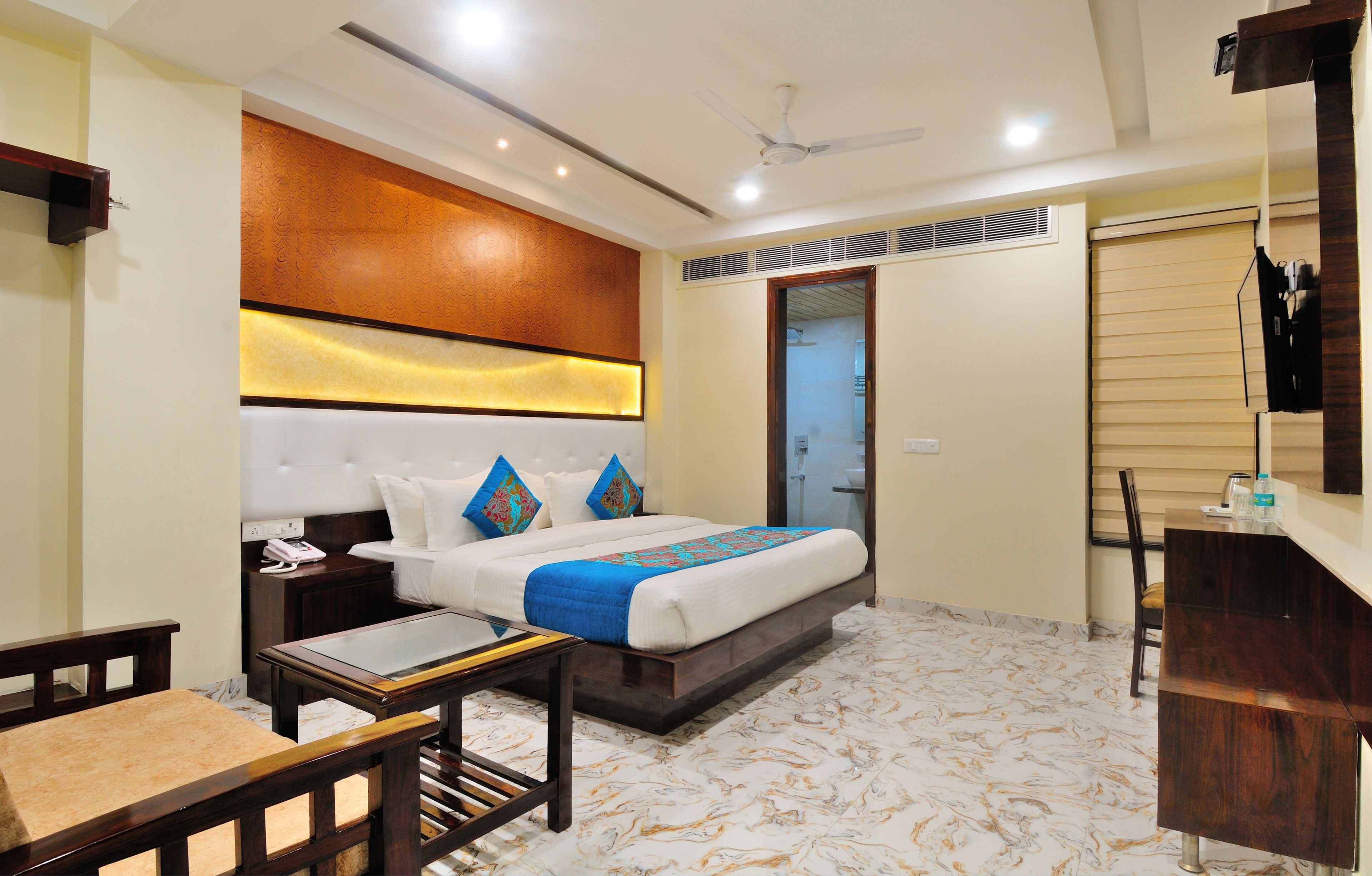 A hotel room with a bed, bedside tables, a desk, and a chair.