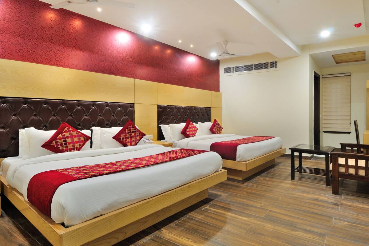 A hotel room with two beds, a wooden headboard, a small table, and a chair.