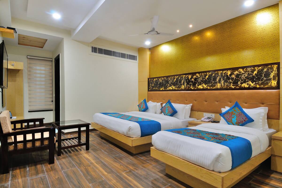 A hotel room with two beds, a desk, and a chair.