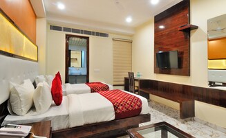 A hotel room with a bed, a TV mounted on the wall, a bathroom with a mirror, and a ceiling fan.