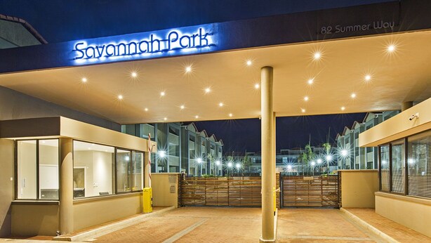 A hotel entrance with a sign reading "Savannah Park" and a brick pathway leading to the entrance.