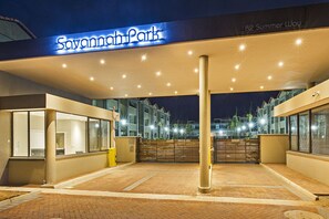 Entrada de un hotel con un cartel que dice "Savannah Park" y un camino de ladrillo que conduce a la entrada.