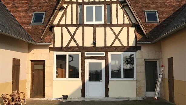 Una casa in stile Tudor con facciata simmetrica, due finestre al piano terra e una porta centrale.