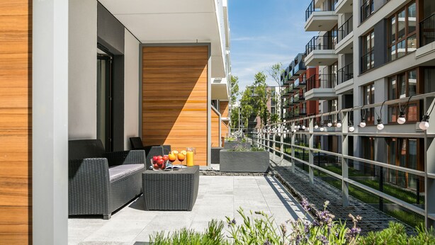 Un espace extérieur moderne, aménagé avec des meubles en osier et agrémenté d’un saladier rempli de fruits.