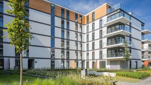 Un immeuble moderne à plusieurs étages, doté de balcons, de grandes fenêtres et d’une cour aménagée.