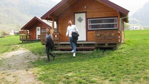 A wooden cabin with a porch, a door, and a window. - Sæbø Camping (Eidfjord)