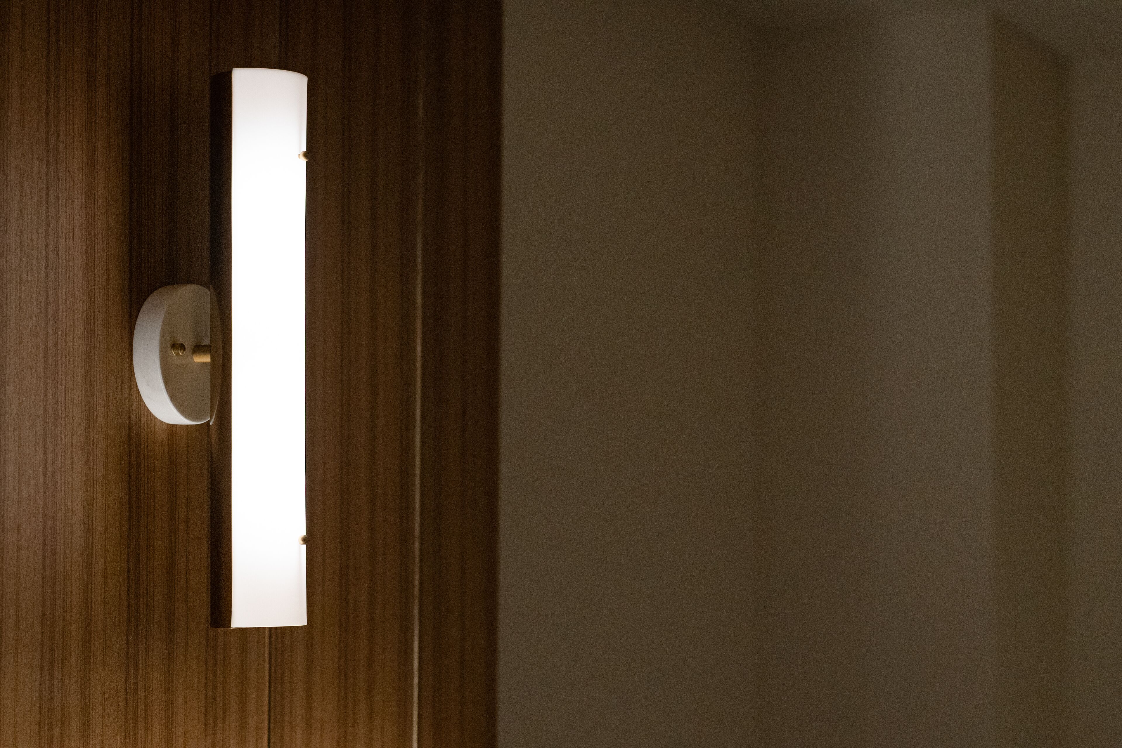 A wall-mounted light fixture in a room with wooden paneling.