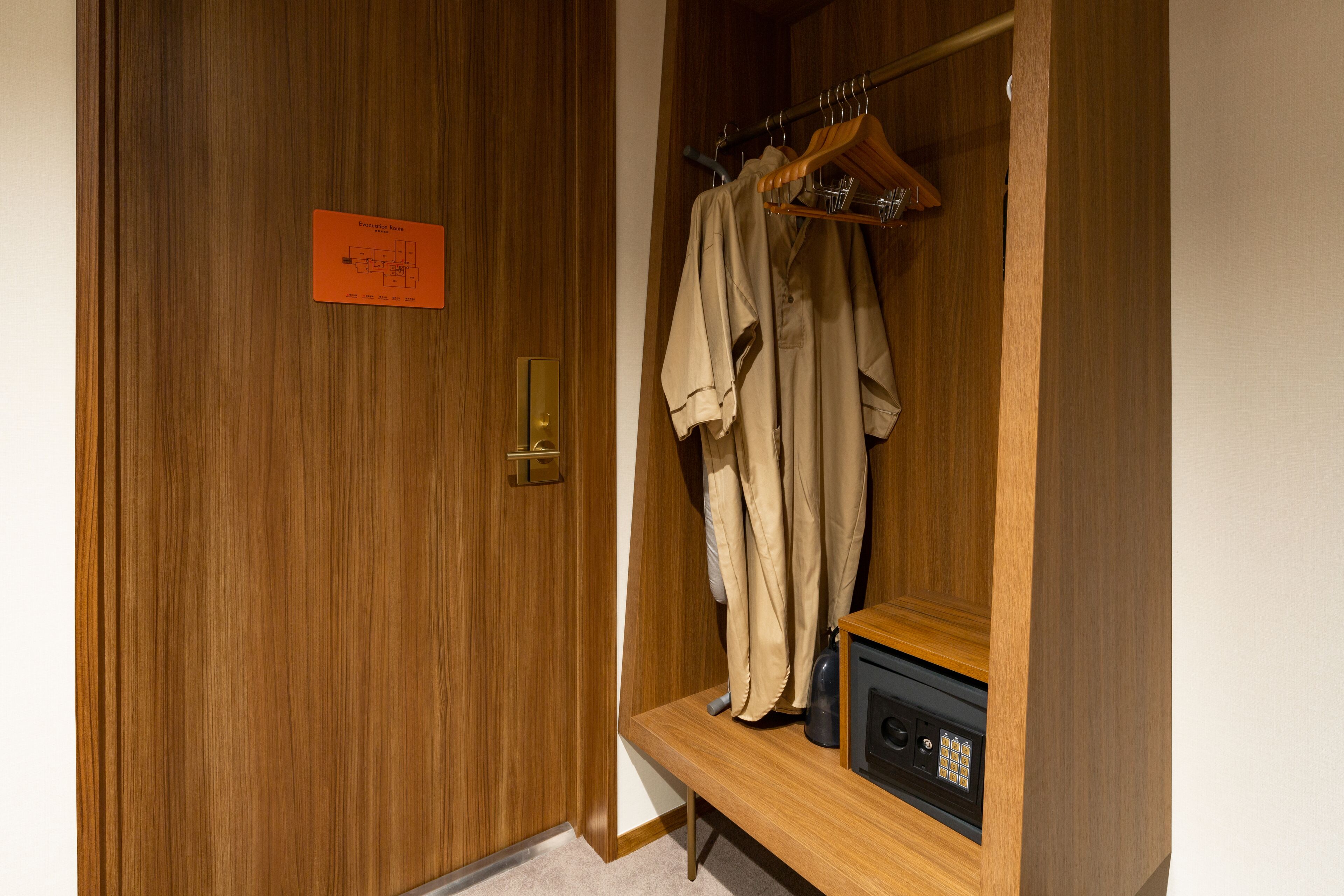 Een houten garderobe met een kledingroede en een klein tafeltje met een radio.