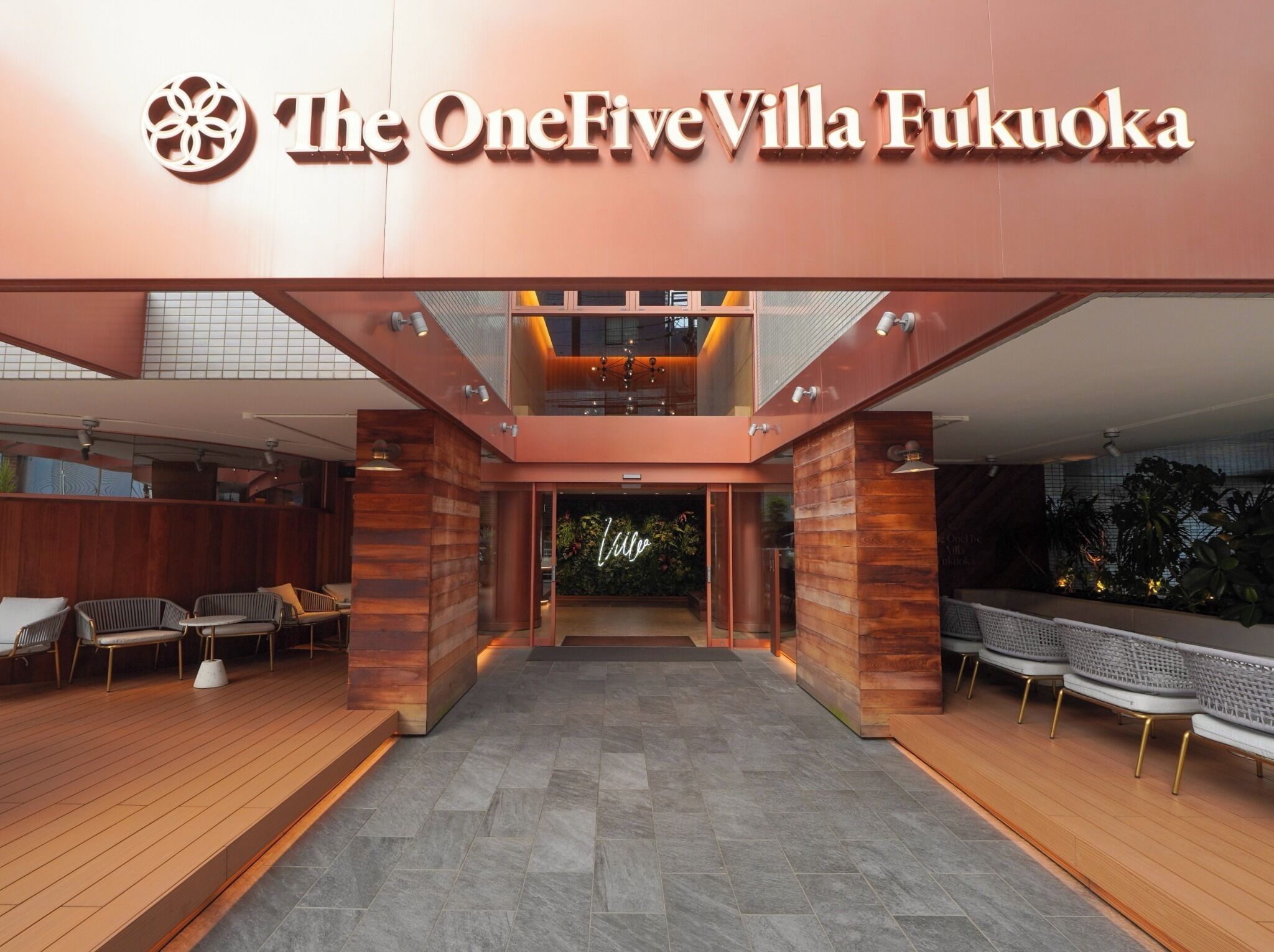 The OneFiveVilla Fukuoka's entrance with a modern design, wooden flooring, and seating areas.