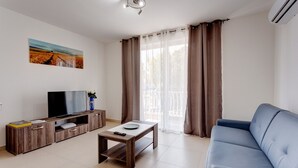 A living room with a TV, wooden cabinet, coffee table, and blue sofa. - Cosy 1BR Apartment in a Central Location (Msida)
