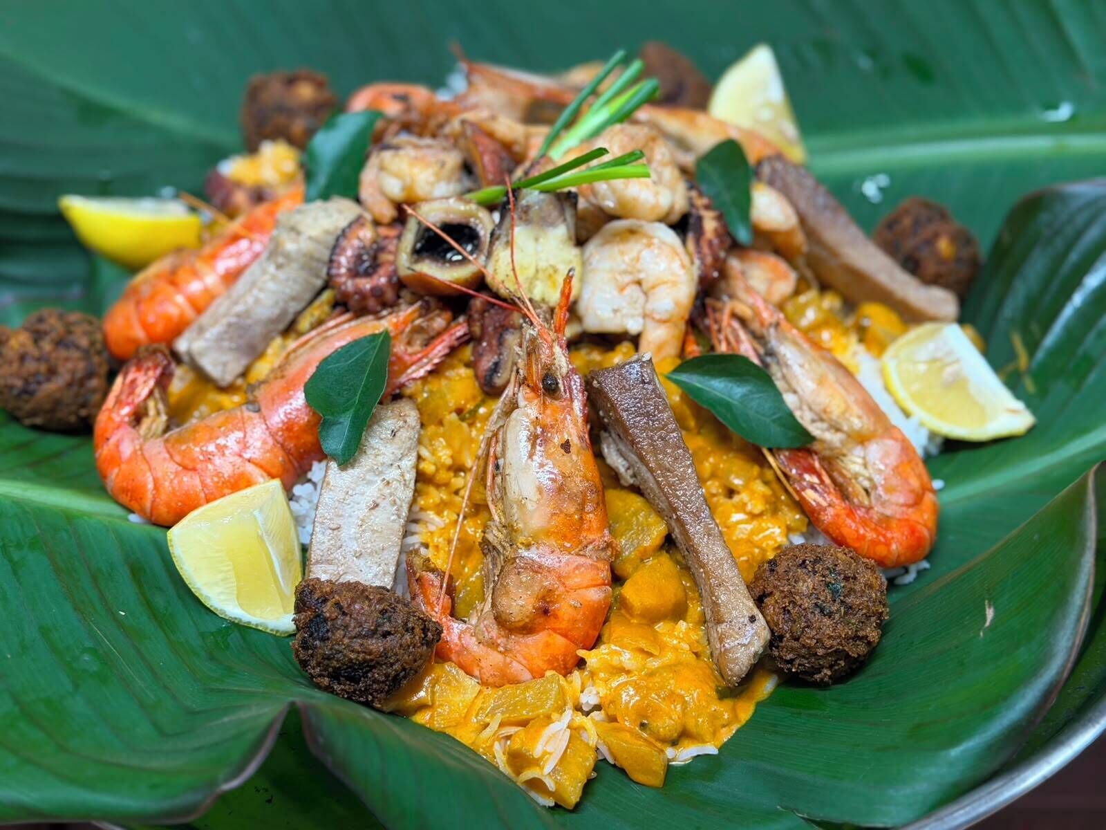 A seafood dish with shrimp, mussels, and other seafood on a banana leaf.