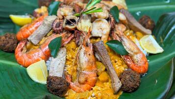 A seafood dish with shrimp, mussels, and other seafood on a banana leaf.