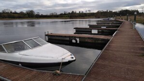 A boat docked at a wooden pier extending into a calm river. - 59 Riverun (Belturbet)