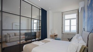 A modern hotel room with a large bed, a TV, a desk, and a window.