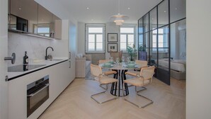 A modern kitchen with a dining area, featuring a large window, a built-in oven, and a dining table set for six.