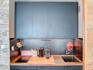 Una cocina con armarios oscuros, salpicadura de ladrillo, encimera de madera y un lavabo.