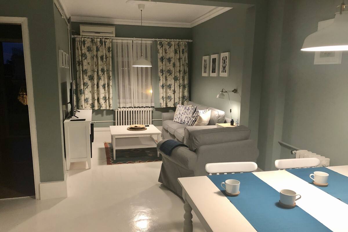 Uma sala de estar moderna com sofá, mesa de centro e mesa de jantar com xícaras.